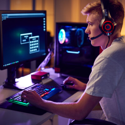 Male,Teenage,Hacker,Sitting,In,Front,Of,Computer,Screens,Bypassing